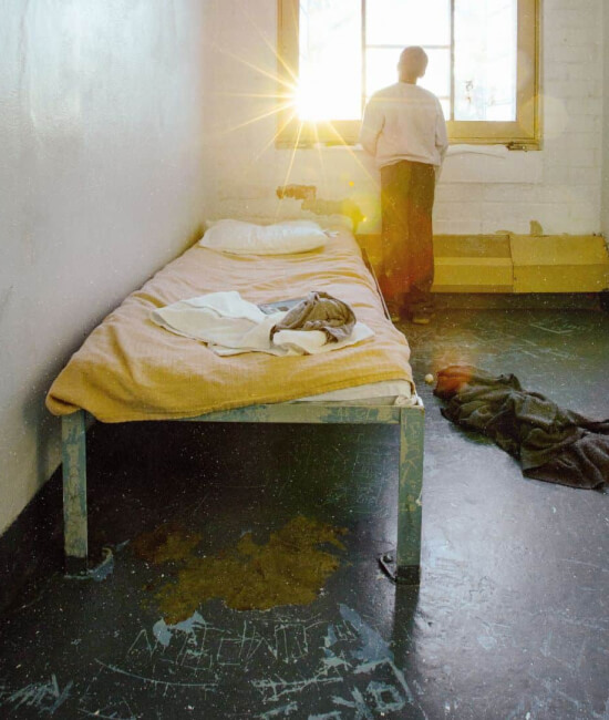 young boy looking out a jail cell window and the sun coming through