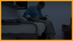 teen boy reading a book in a jail cell