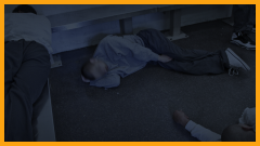many young teen boys sleeping on the floor and on benches in a holding cell