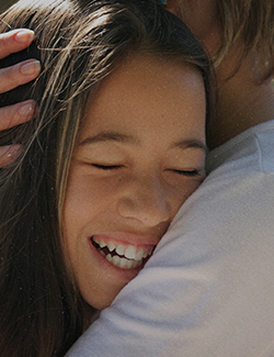 Human Rights for Kids Girl smiling while hugging an adult